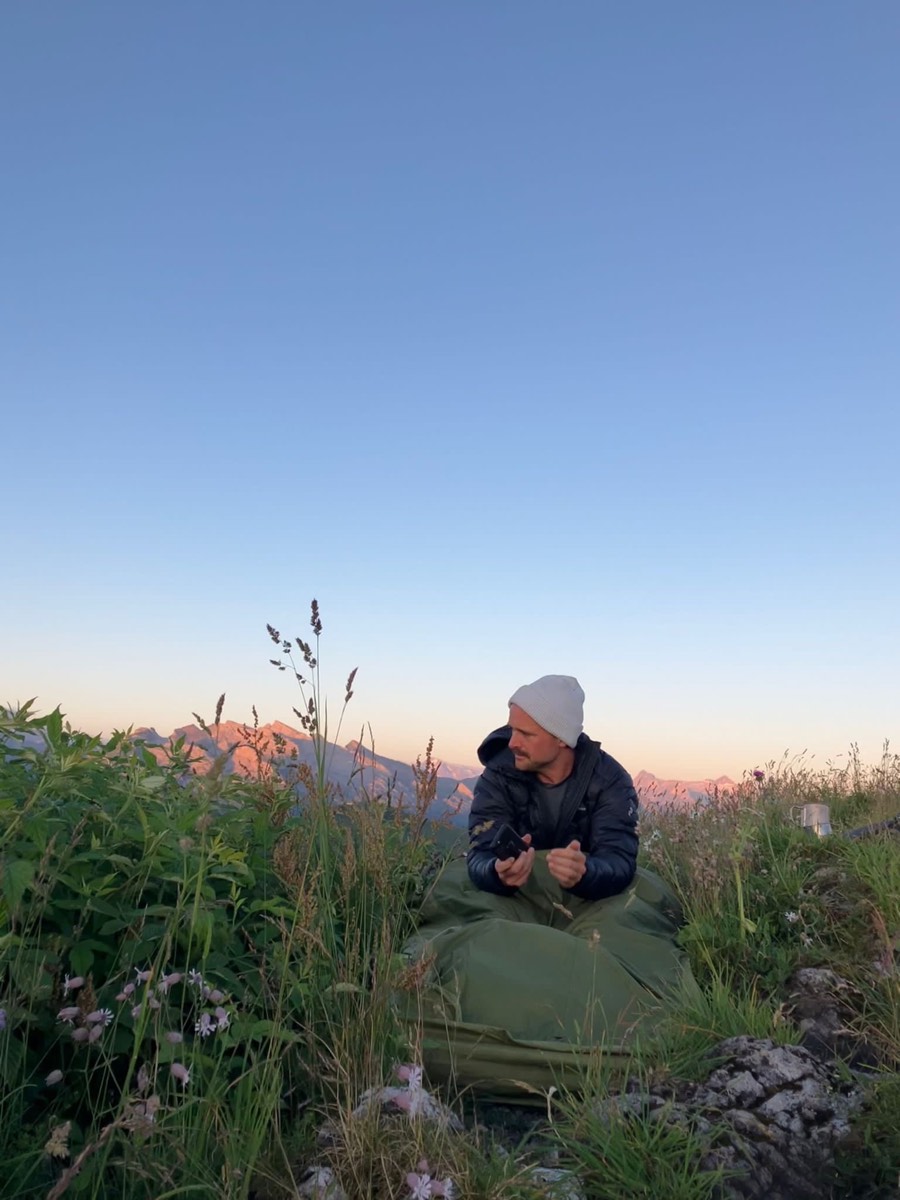 Person im Biwak zwischen Alpenblumen