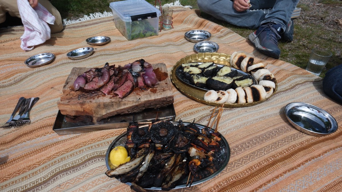 Gegrilltes Fleisch, Gemüse und Fisch auf Platten am Boden